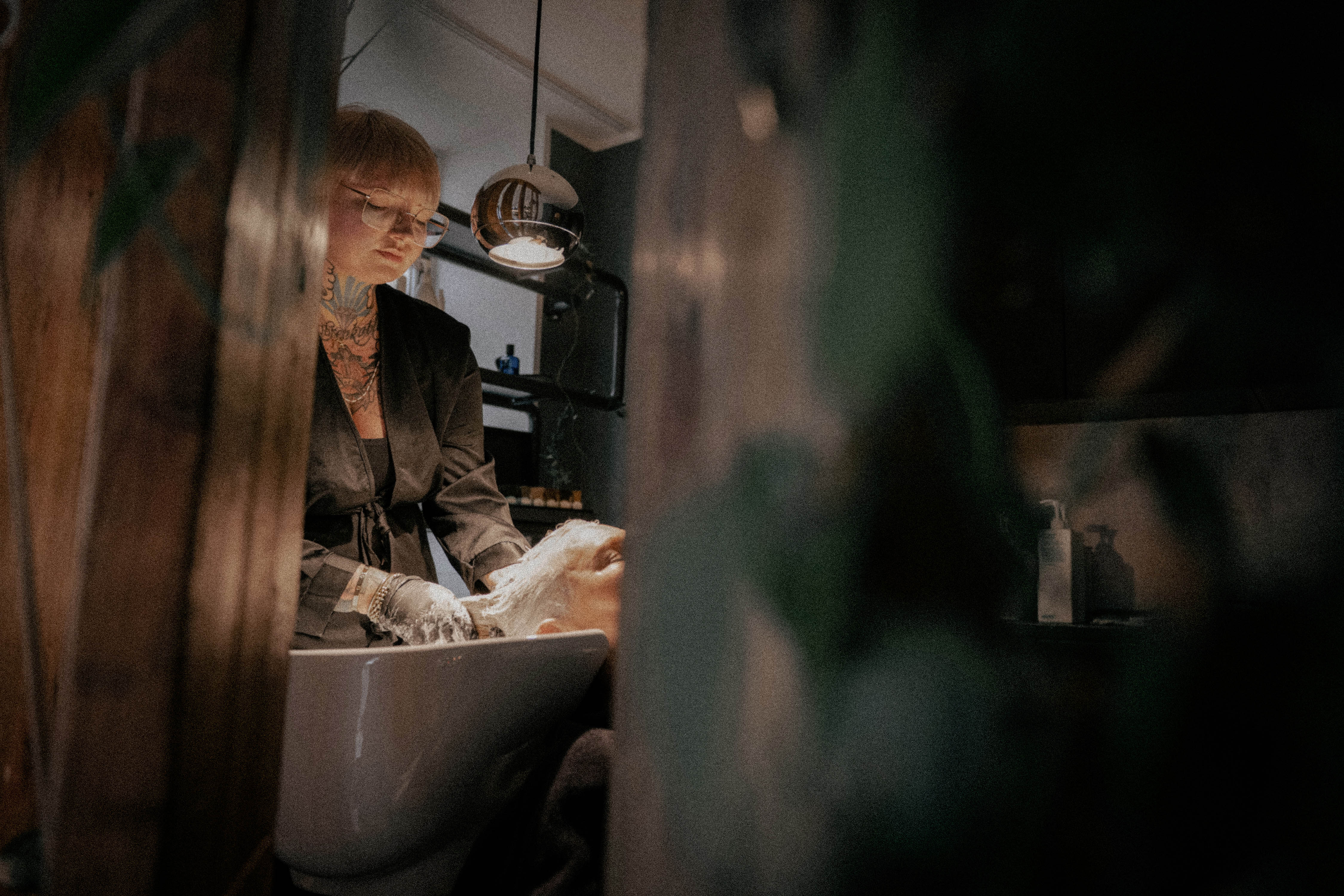 Friseurin wäscht der Kundin die Haare am Waschbecken im Friseursalon.